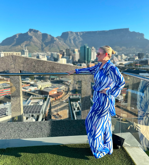 Cheryl at the rail of a hotel terrace above Cape Town, Table Mountain
                    across the city behind her