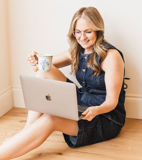 Cheryl working from a sunlit corner with a laptop and a cup of tea
