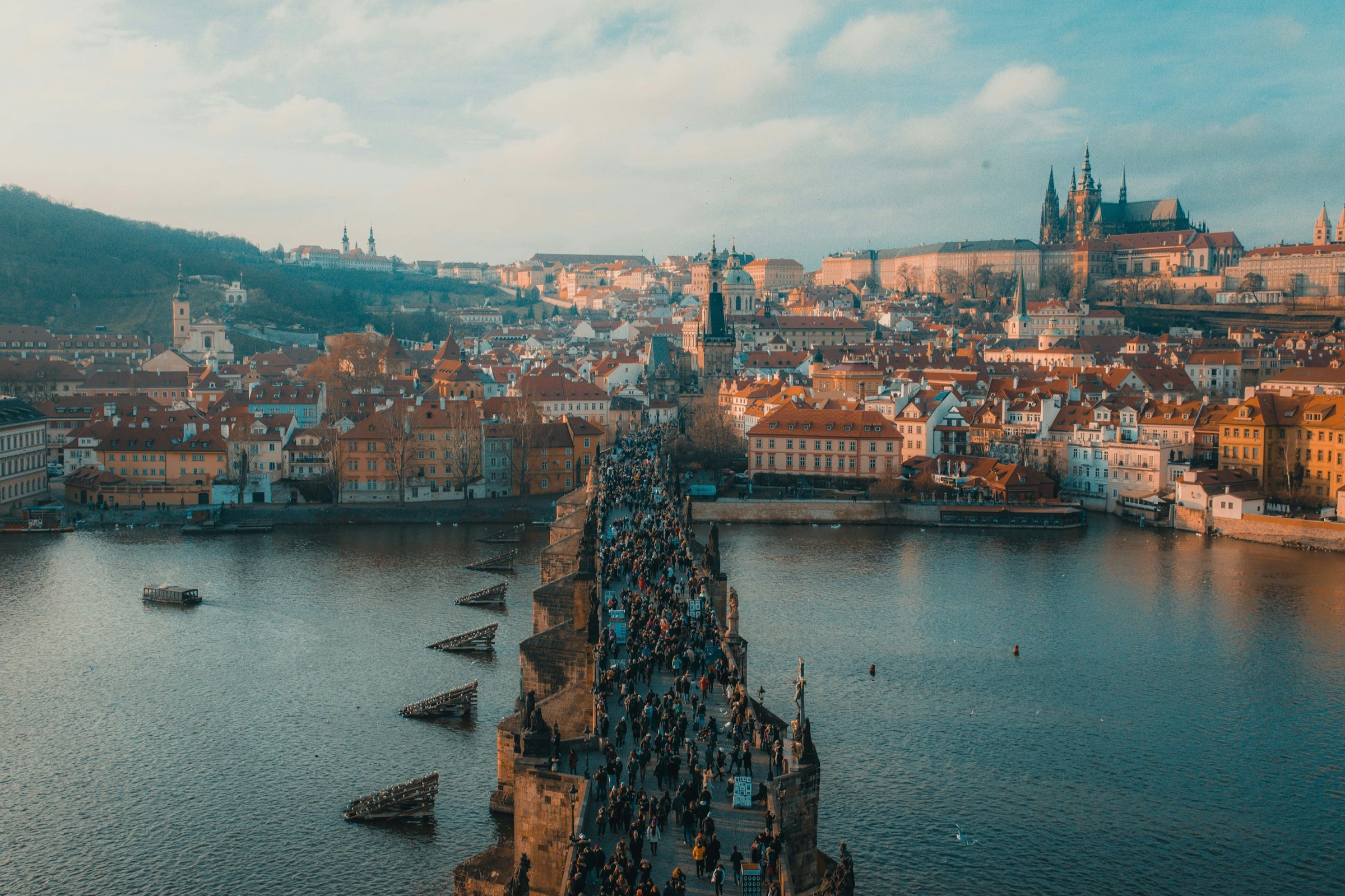 Terracotta rooftops and a river bridge seen from above at golden hour