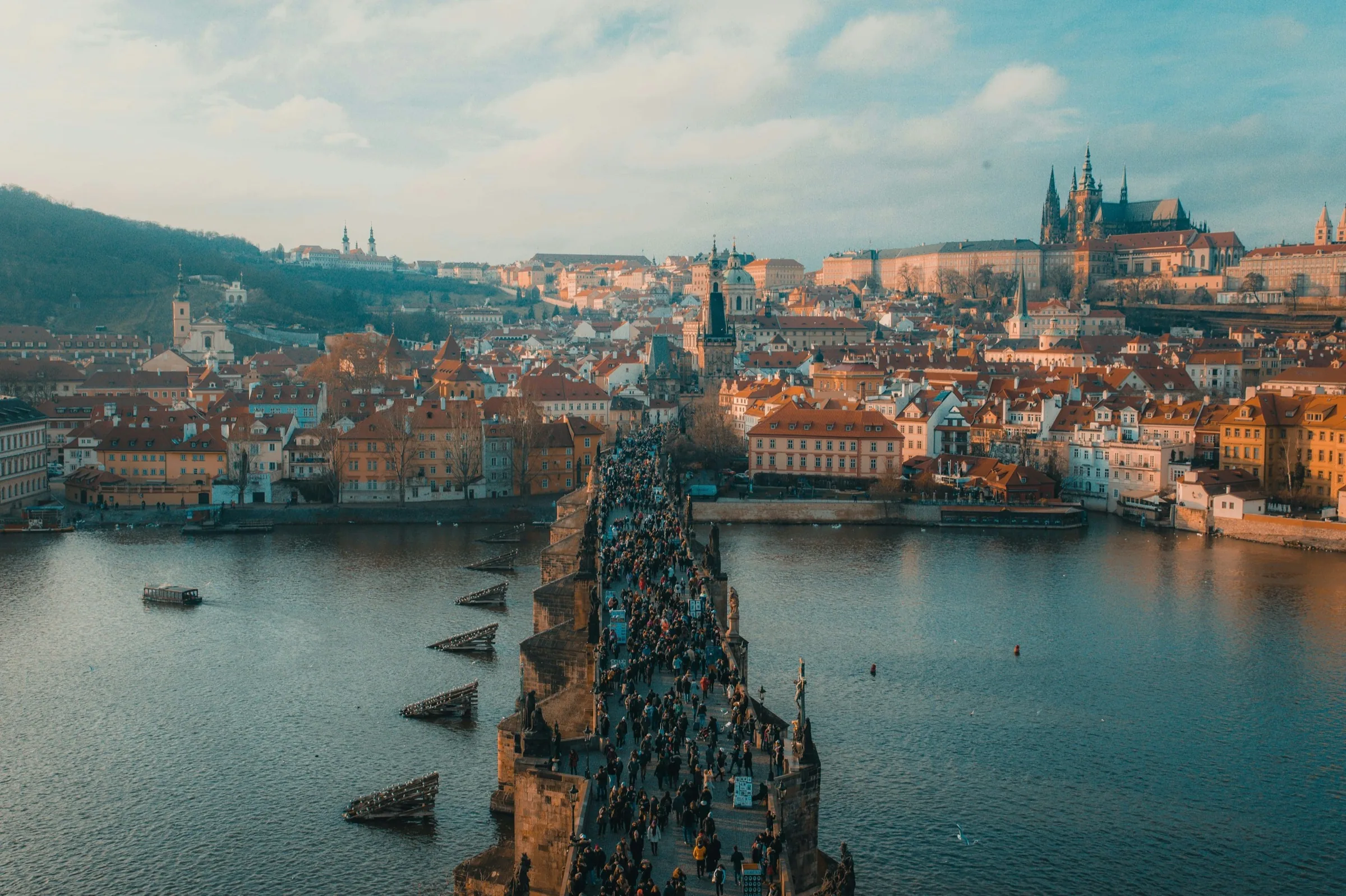 Terracotta rooftops and a river bridge seen from above at golden hour