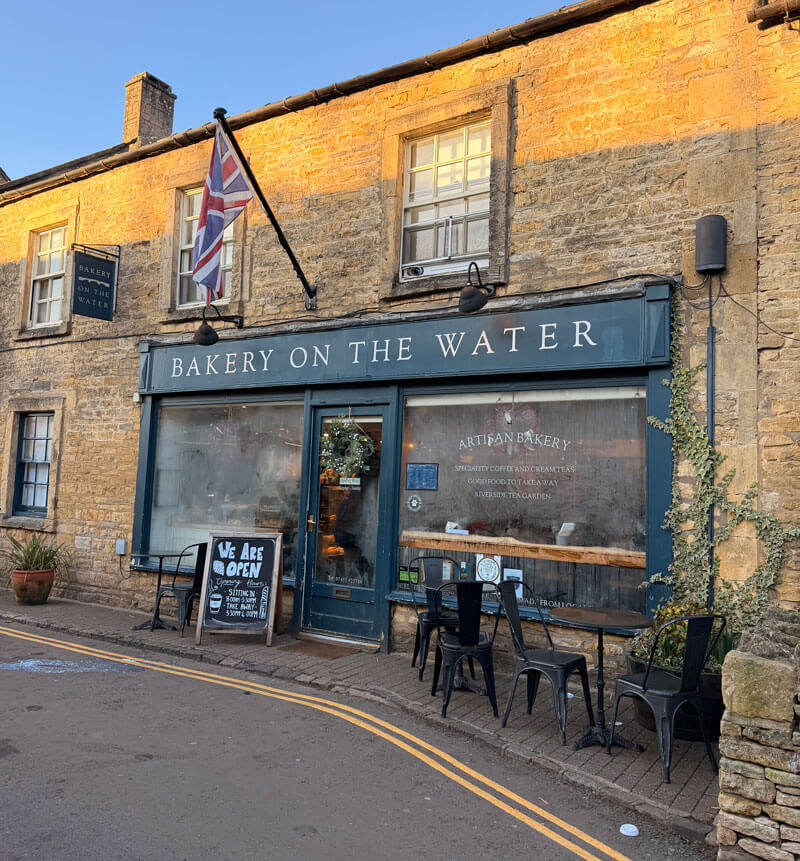 A blue-fronted bakery beside the water in Bourton-on-the-Water
