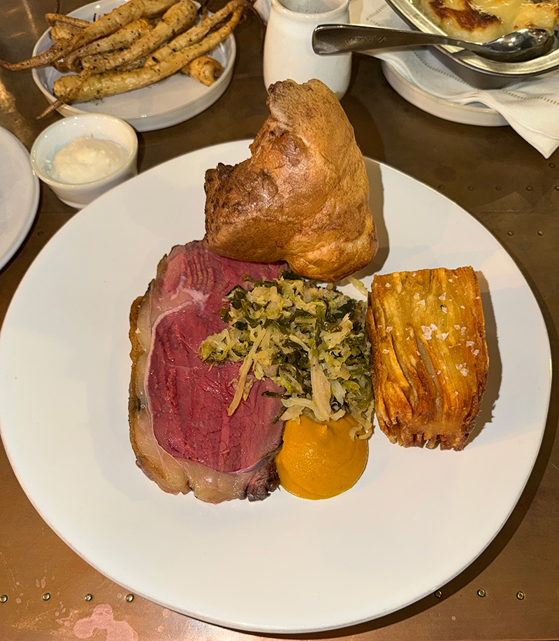 A Sunday roast plated with beef, Yorkshire pudding, vegetables and gravy