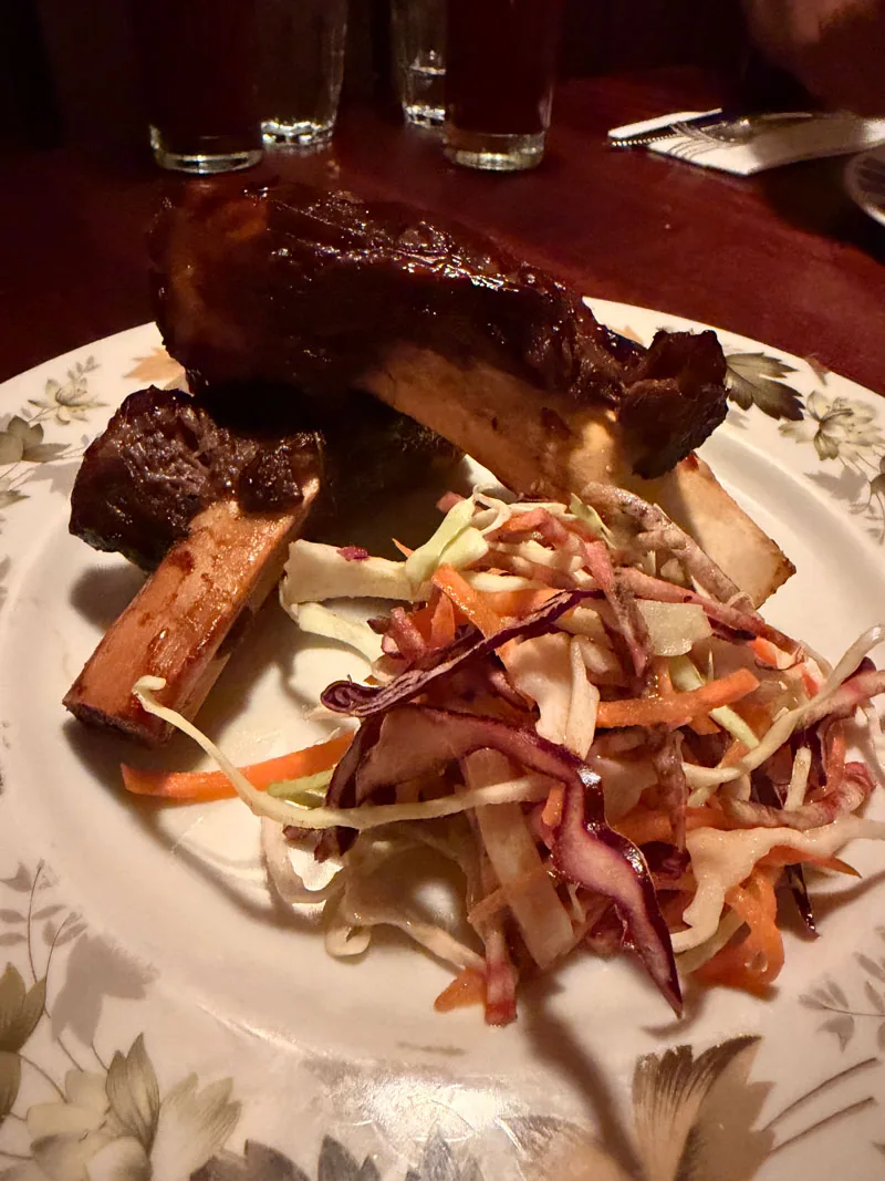 Smoked Beef Ribs at Blacklock Covent Garden, glazed and sticky with the bone in, served on a floral plate with Summer Slaw