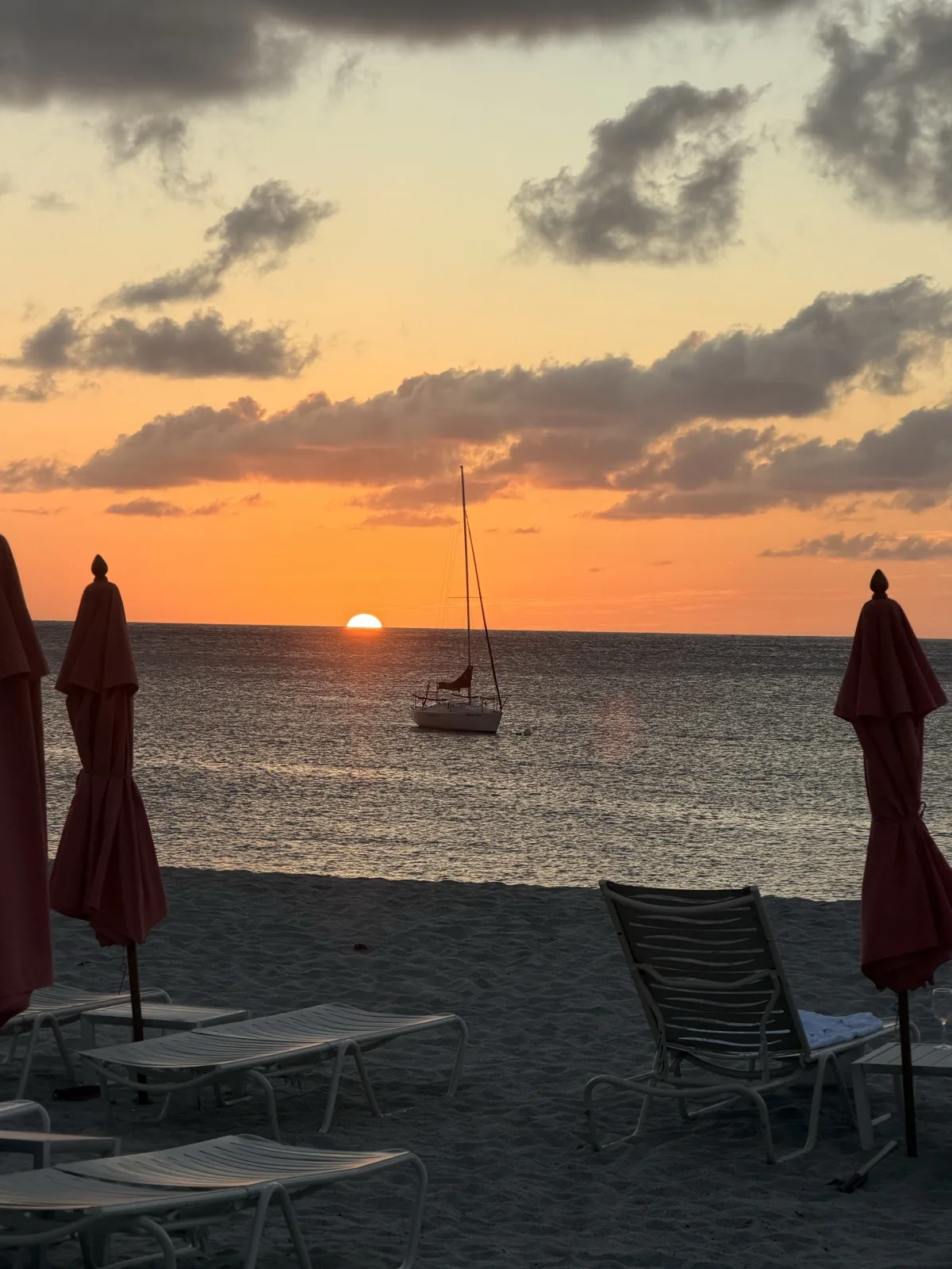 Sunset over the beach, a yacht anchored offshore and the sun loungers stacked on the sand