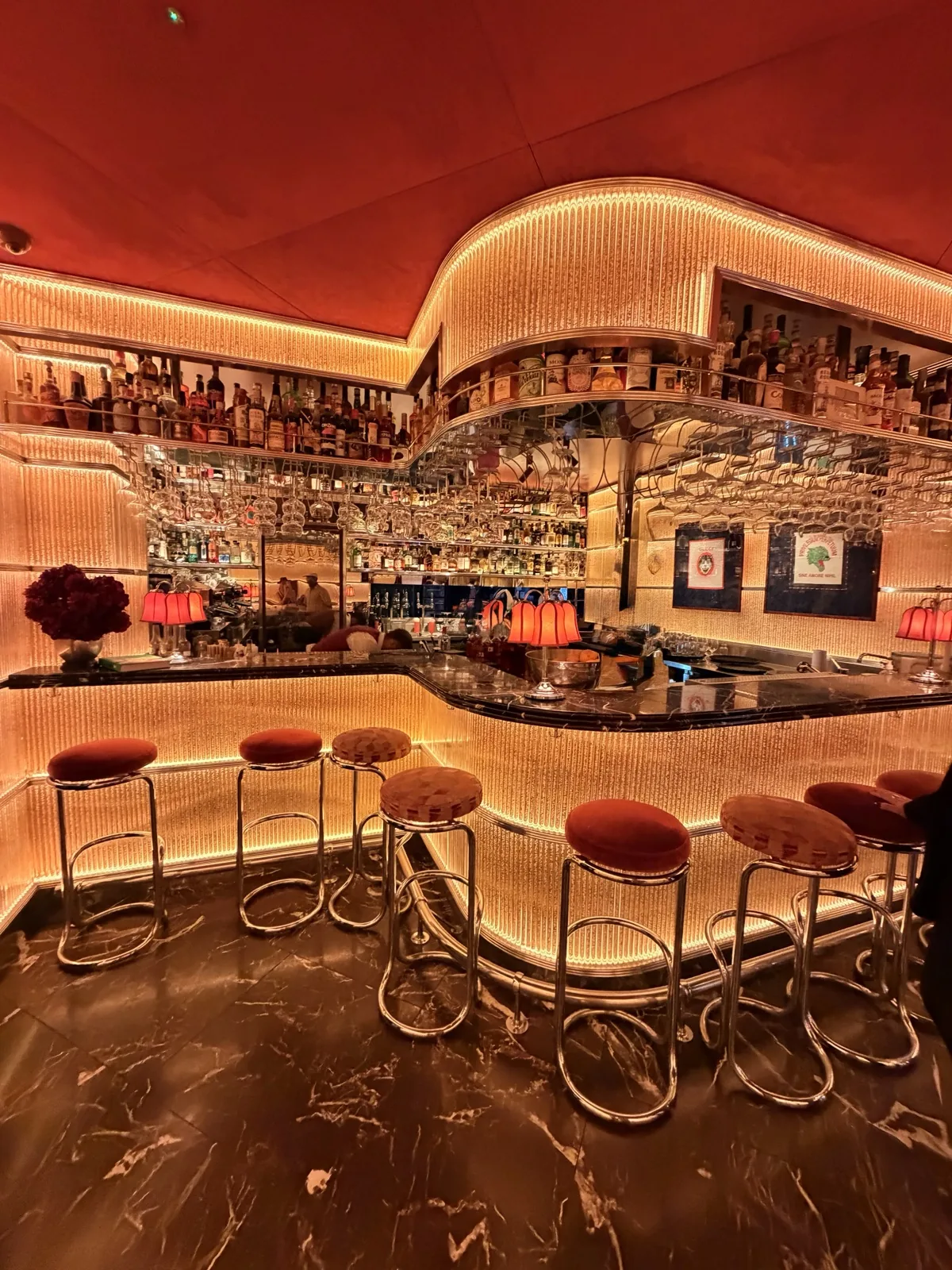 The Rosso Levanto marble bar at Carlotta Marylebone, lit gold beneath fringed curtains