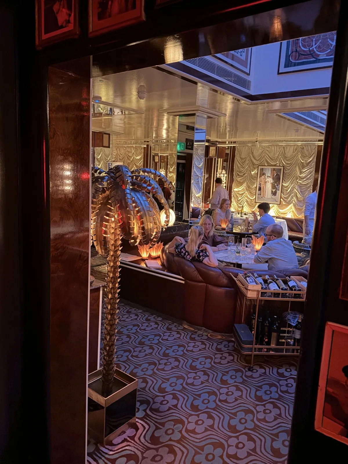 Looking through into the Carlotta dining room past a gilded palm lamp and patterned floor