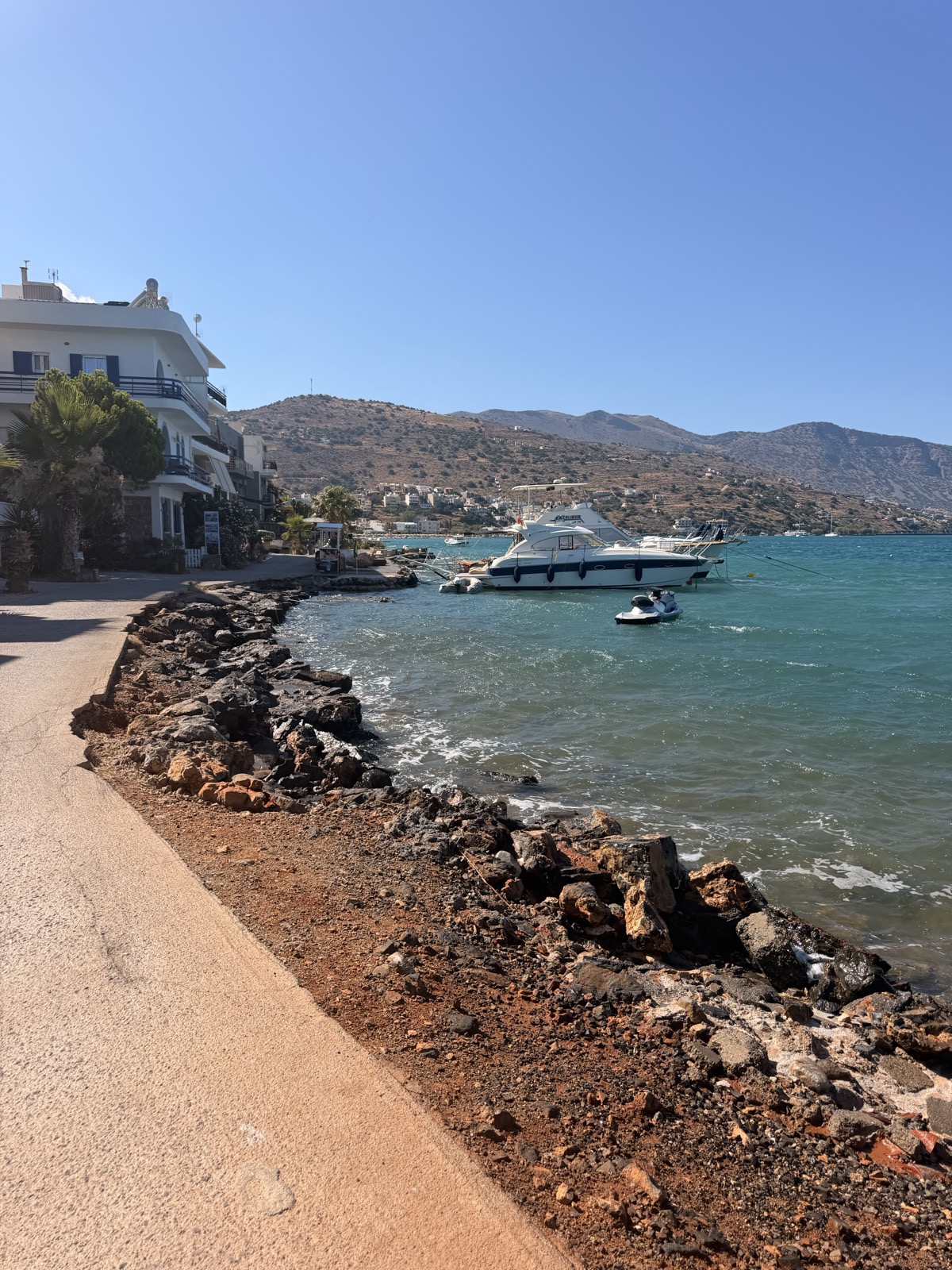 Boats moored along the rocky shoreline in Elounda town, Crete