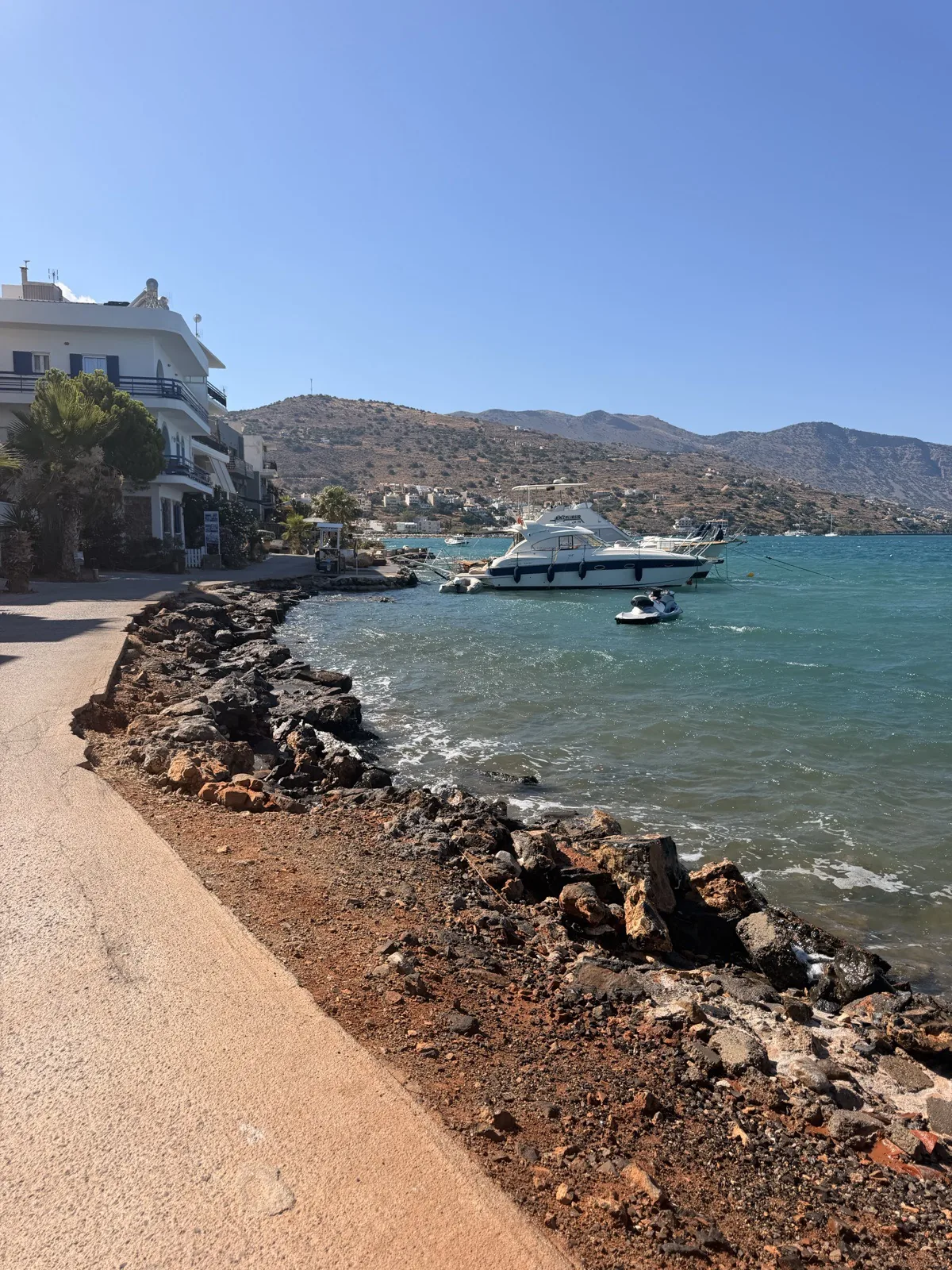 Boats moored along the rocky shoreline in Elounda town, Crete