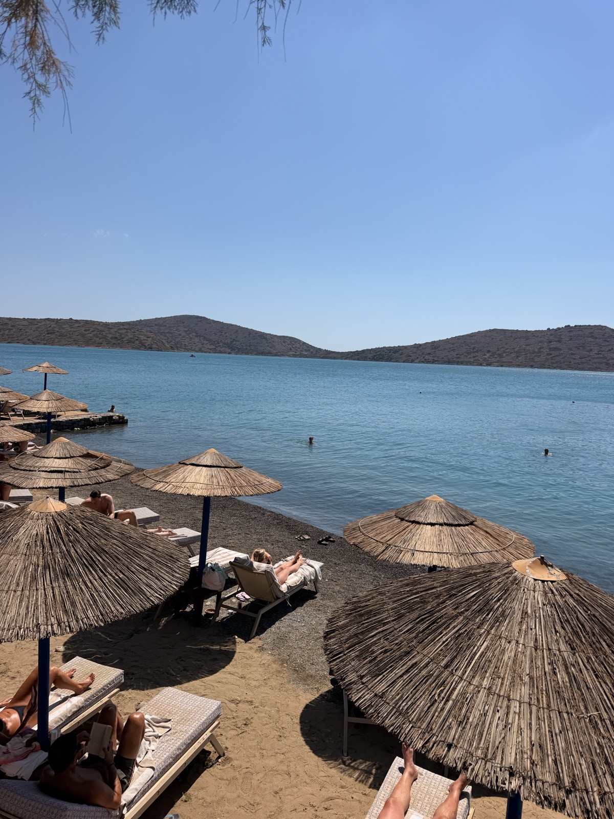 Calm turquoise water and straw parasols on the public beach in Elounda town, ten minutes from the resort