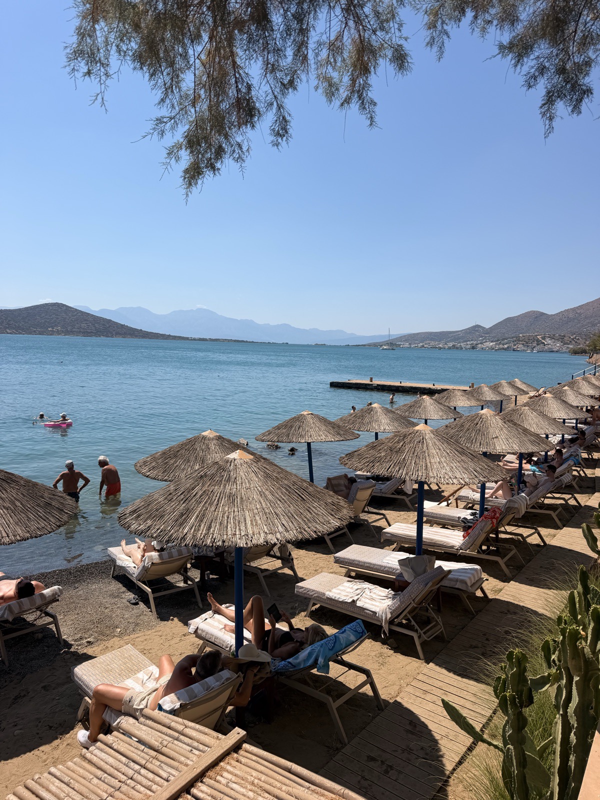 Thatched parasols and sun loungers on the private beach at Domes Aulus Elounda in Crete