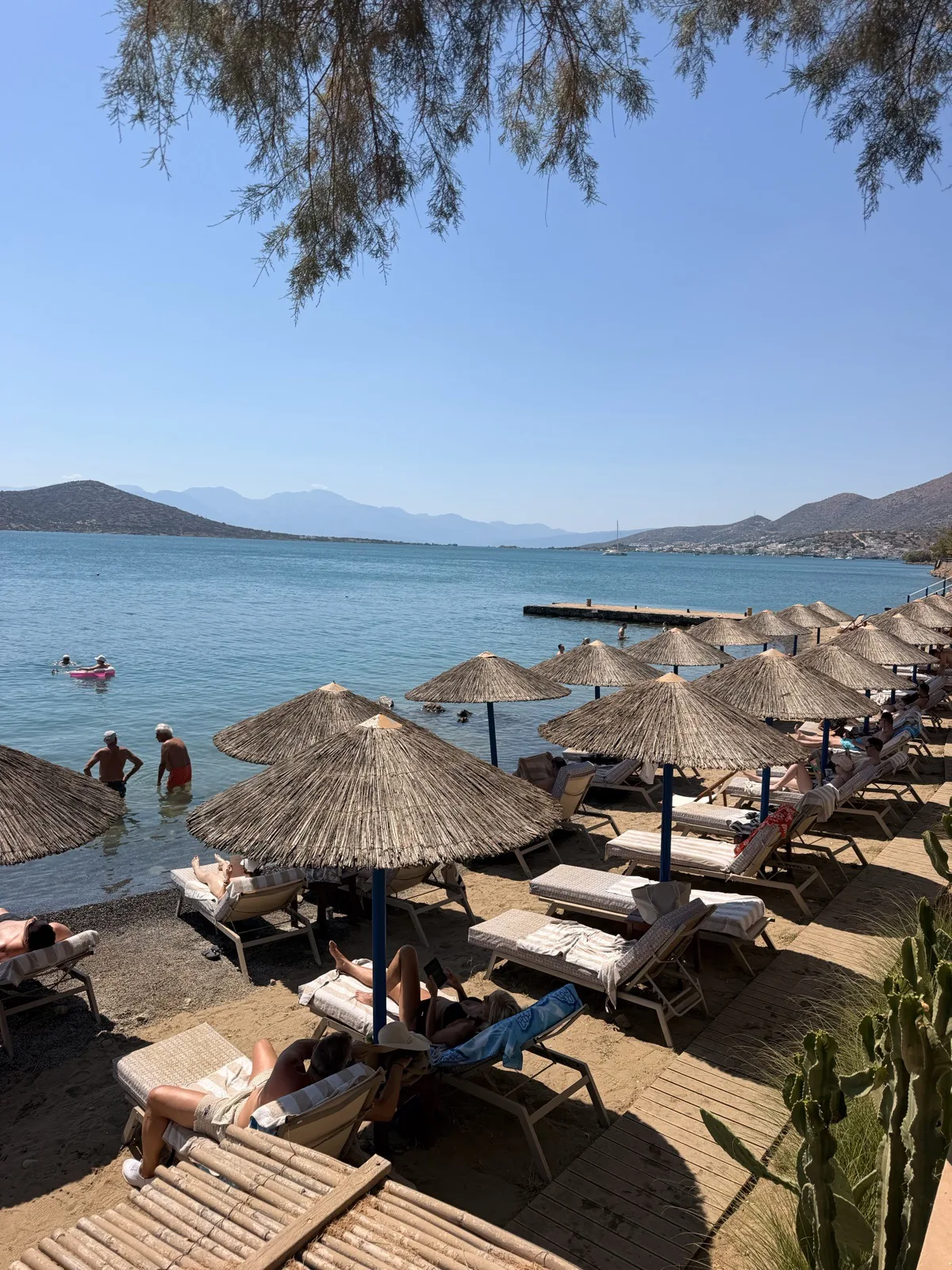 Thatched parasols and sun loungers on the private beach at Domes Aulus Elounda in Crete