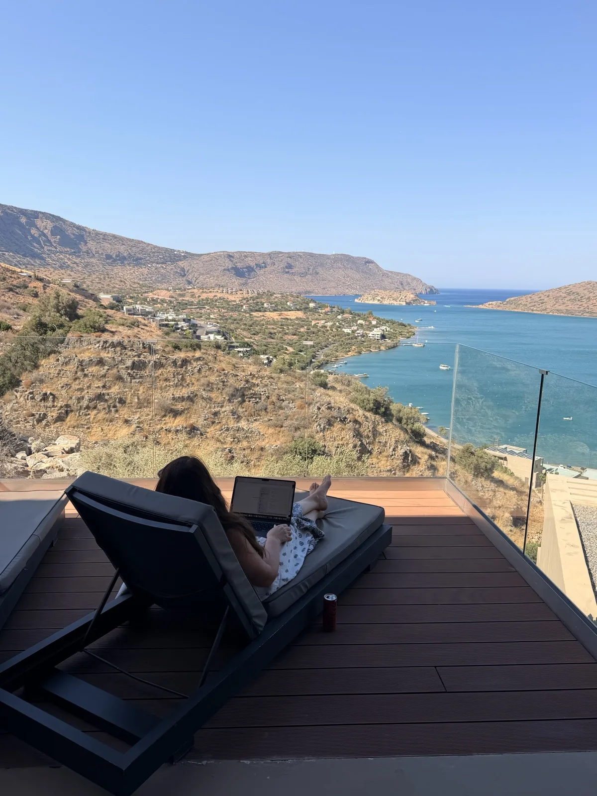 Rooftop pool and wooden sun loungers at Domes Aulus Elounda overlooking the sea at golden hour
