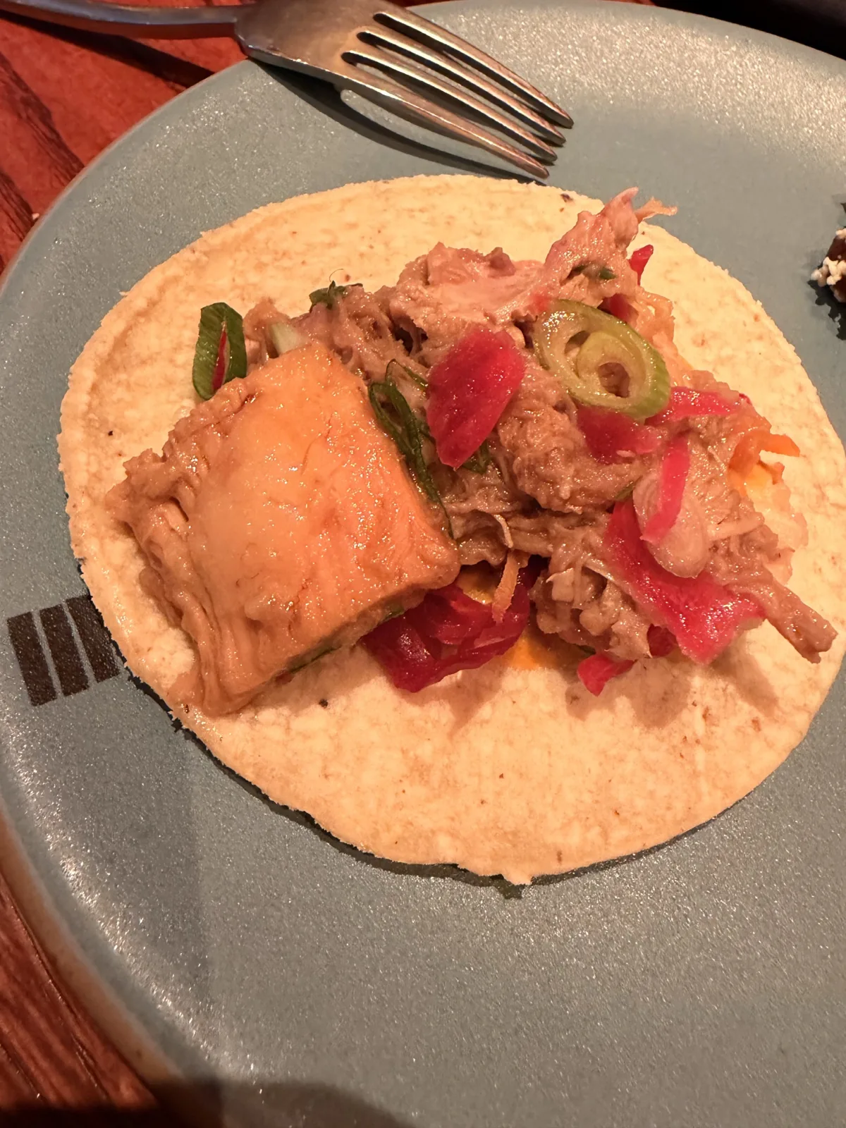 A pork shoulder carnitas taco built on a corn tortilla at Fonda Mayfair, with pickles and crackling on top