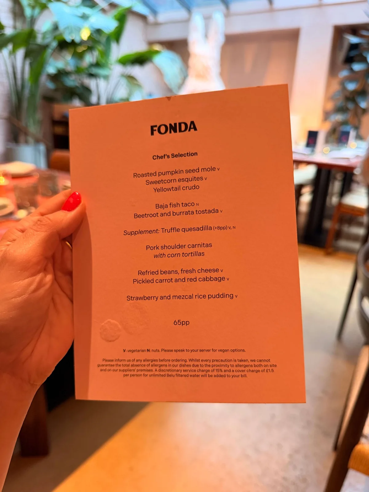 The Fonda chef's selection menu card held up in the dining room, nine savoury plates and a dessert for sixty five pounds a head