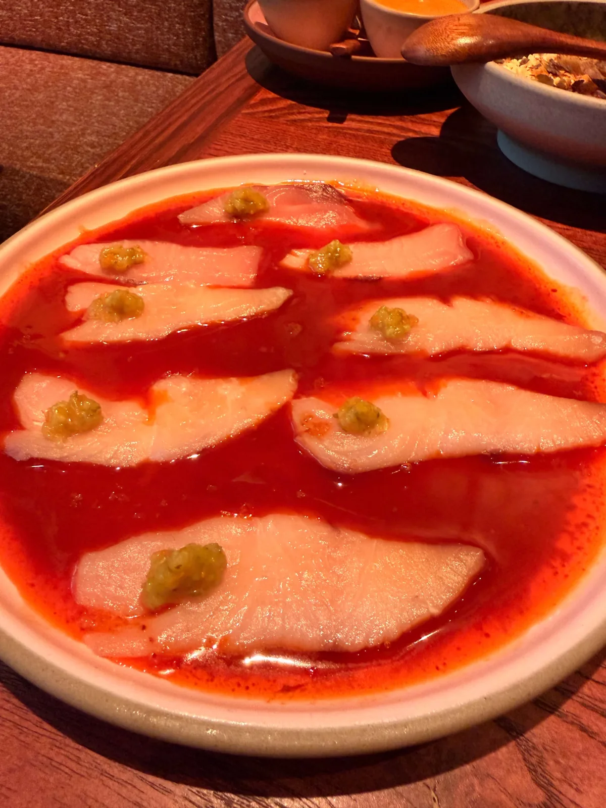 Yellowtail crudo at Fonda Mayfair, thin slices of raw fish in a bright red chilli sauce with green salsa dollops on top