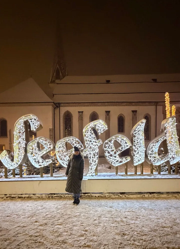 Standing in the snow in front of the giant illuminated SEEFELD letters at night, with the lit church behind