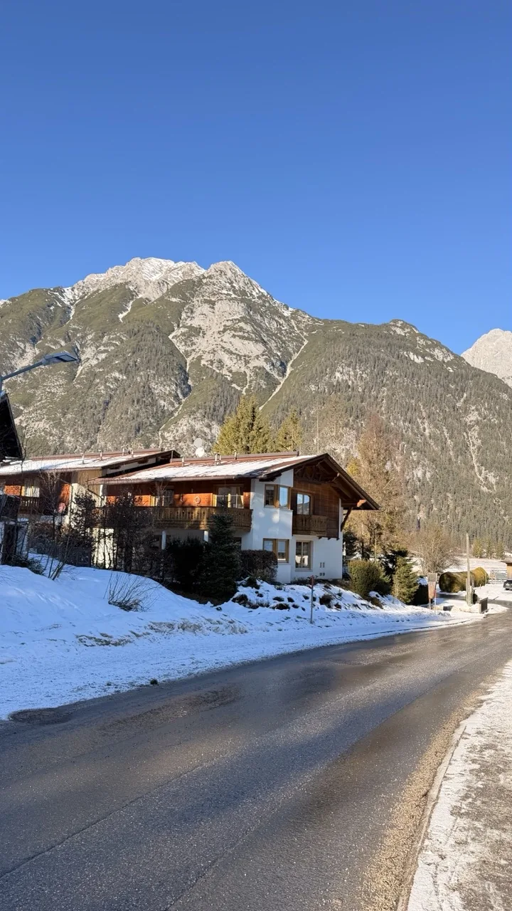 The Karwendel mountains rising above the snow covered chalet roofs of Leutasch under a clear winter sky