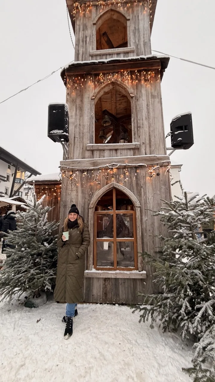 A tall carved wooden tower lit up at the Seefeld Christmas market in the snow