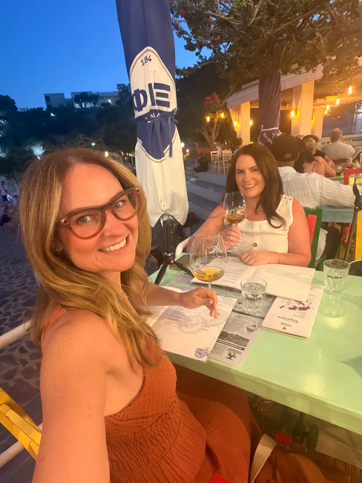 Cheryl and Pam with glasses of amber wine at their front row table above the lake at Karnagio