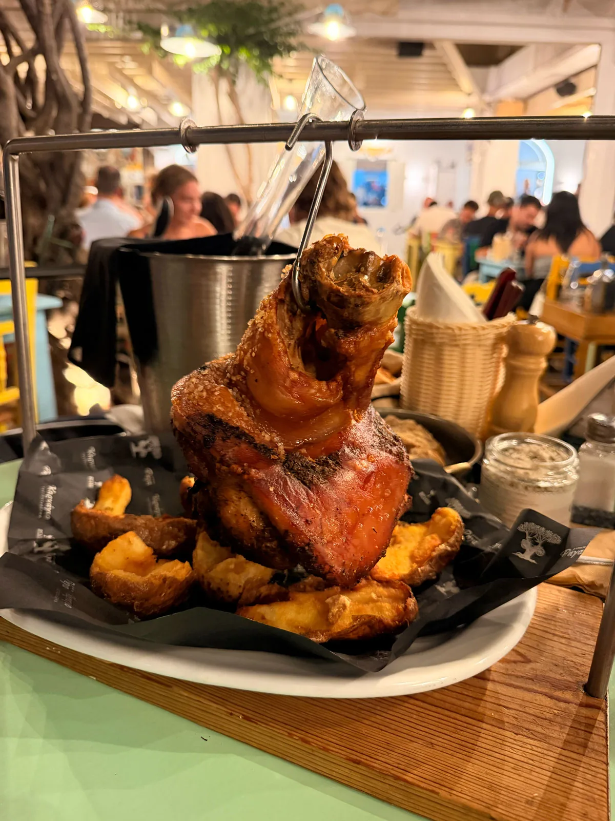 The ten hour pork shank arriving at the table hanging from a hook on its own metal stand, over crispy skin on potatoes