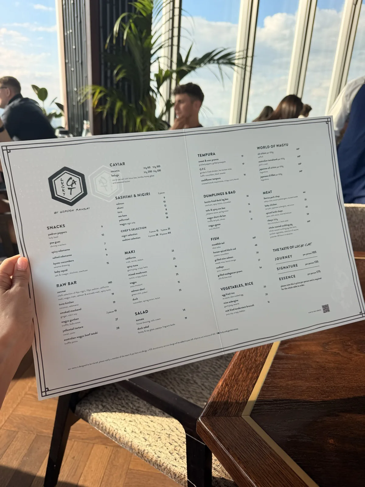 The Lucky Cat a la carte menu held up against the London skyline from Level 60