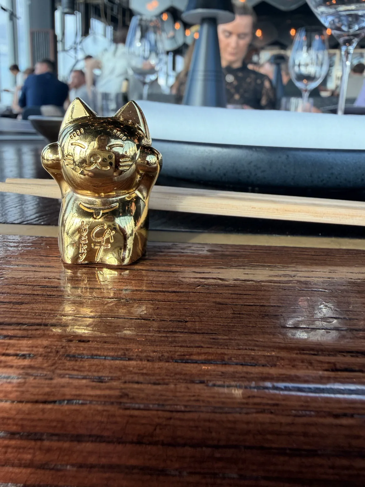 A small gold lucky cat ornament on the dark timber table at Lucky Cat, 22 Bishopsgate
