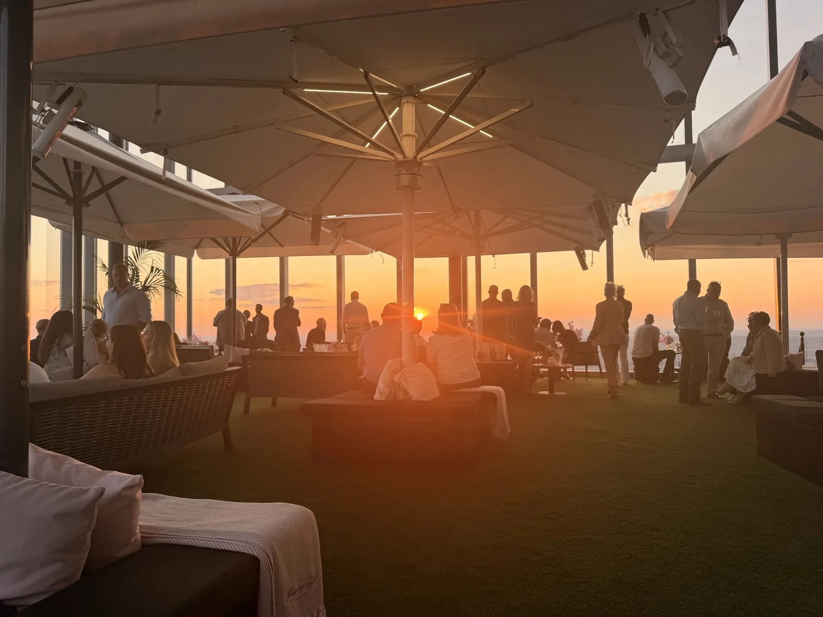 The Lucky Cat Terrace above 22 Bishopsgate at sunset, with parasols, garden sofas and artificial grass