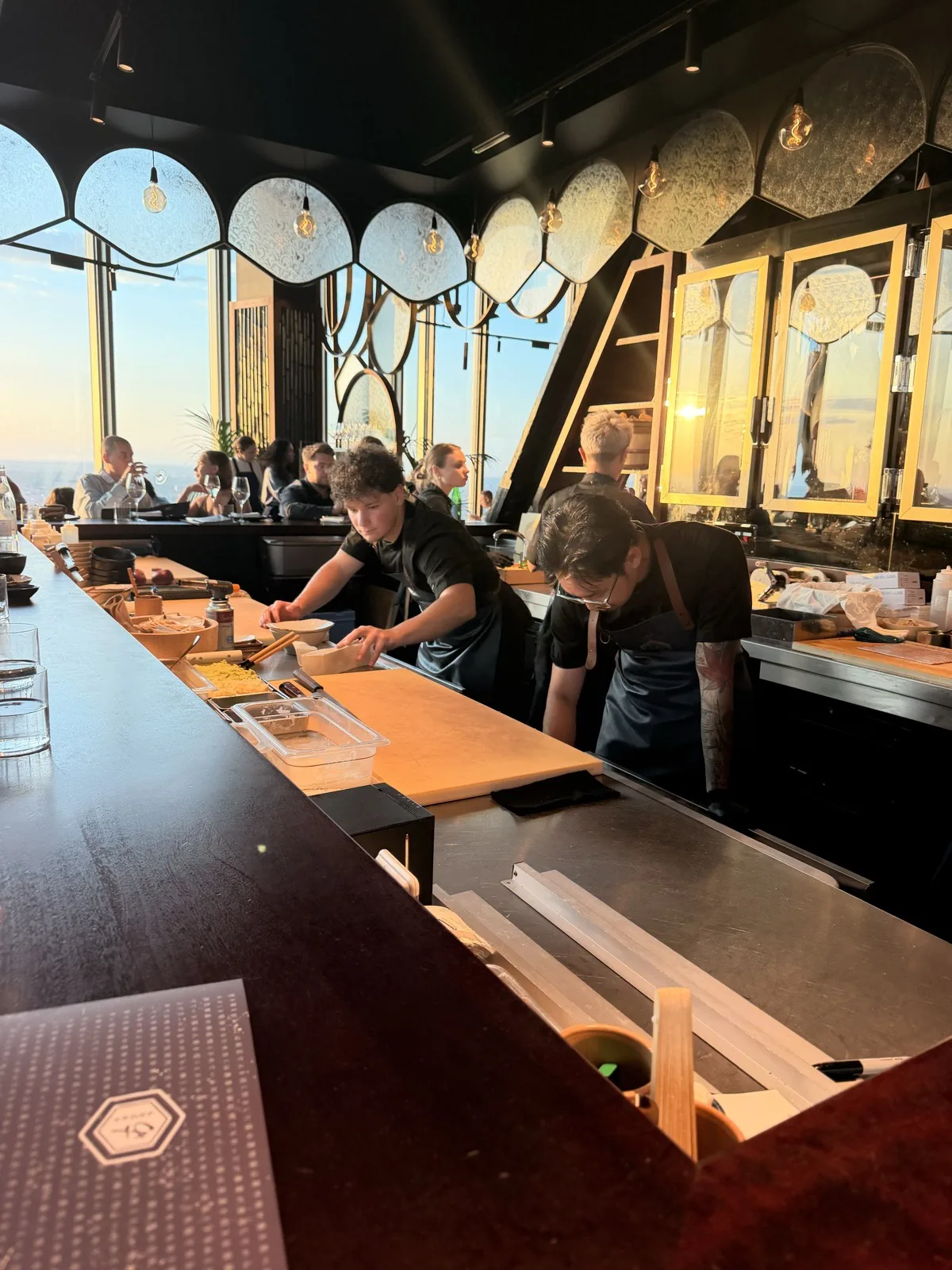 The open sushi bar at Lucky Cat 22 Bishopsgate, chefs working in full view against a wall of hand painted Japanese style fans and plates
