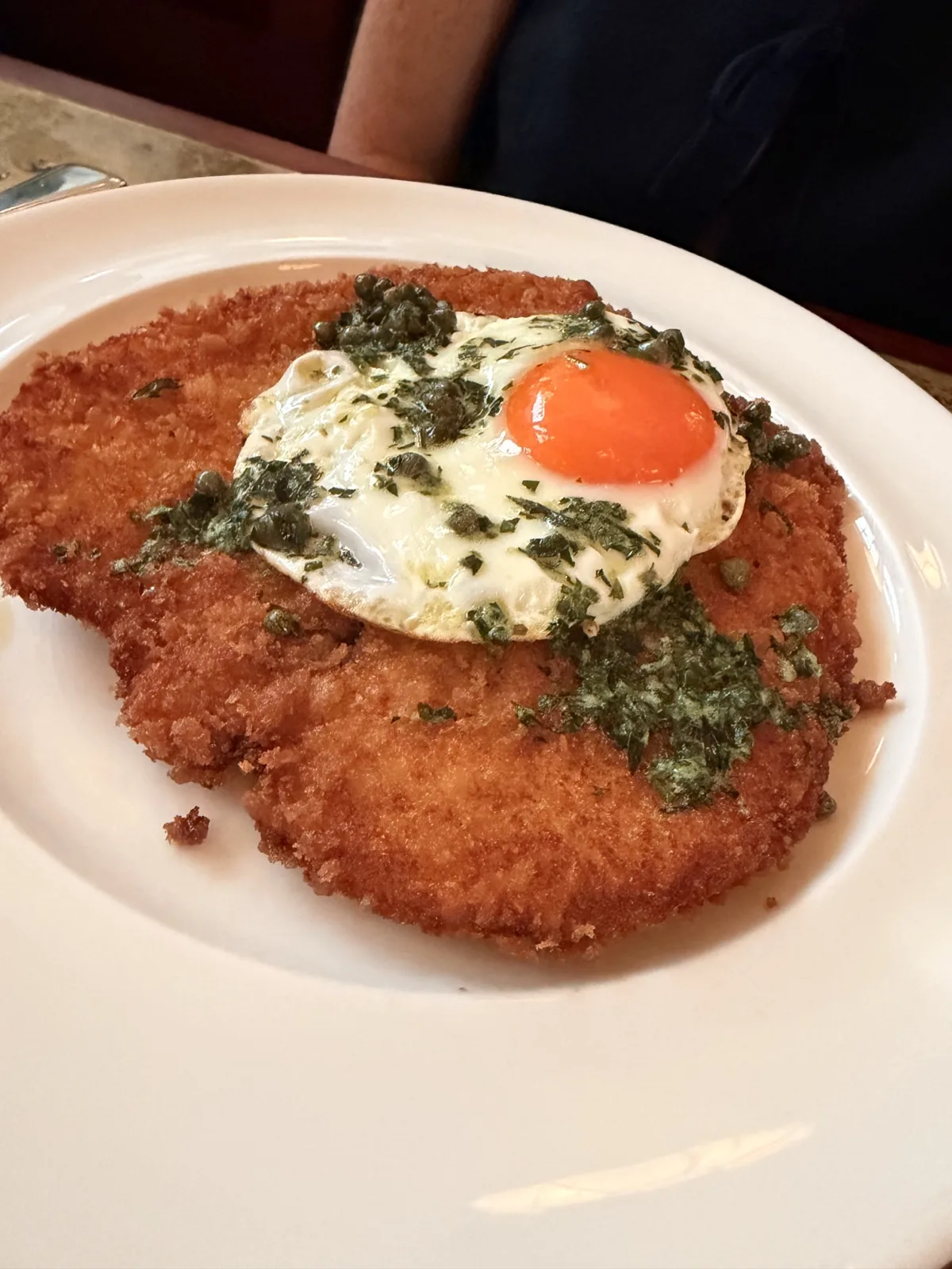 Breaded chicken breast at Millie's Lounge, a flattened schnitzel topped with a fried egg, capers and herb butter