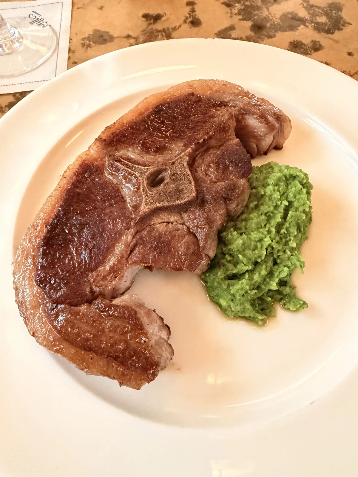 The lamb Barnsley chop at Millie's Lounge, dark and glossy outside and pink in the middle, beside a heap of crushed minted peas