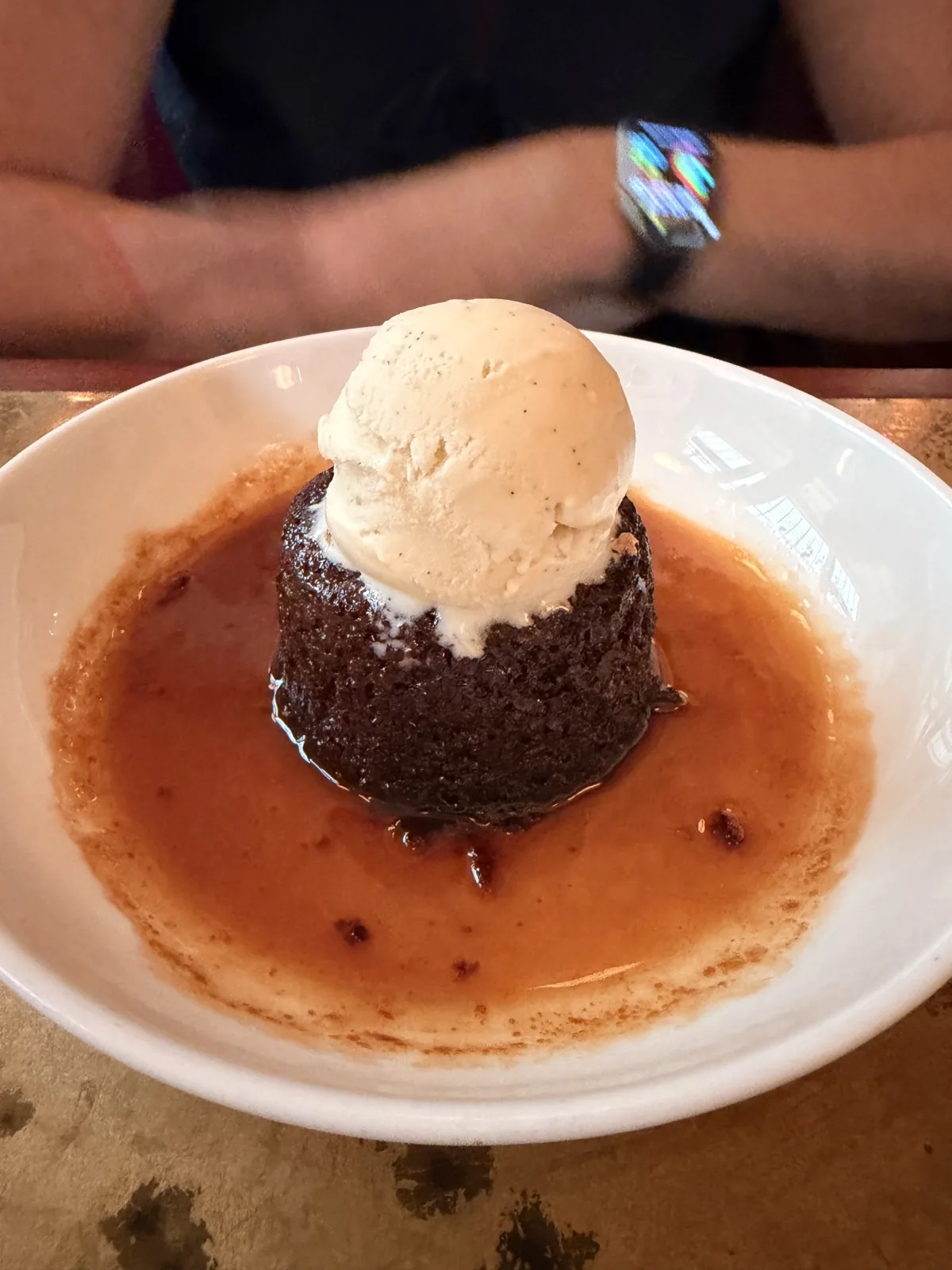 Sticky toffee pudding at Millie's Lounge sitting in a pool of toffee sauce with vanilla ice cream melting off the top