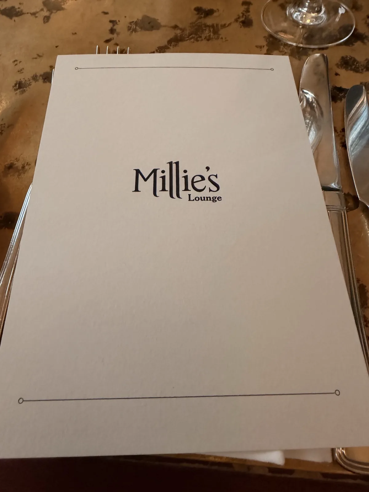 The Millie's Lounge menu on the worn gold leaf table at The Ned, City of London