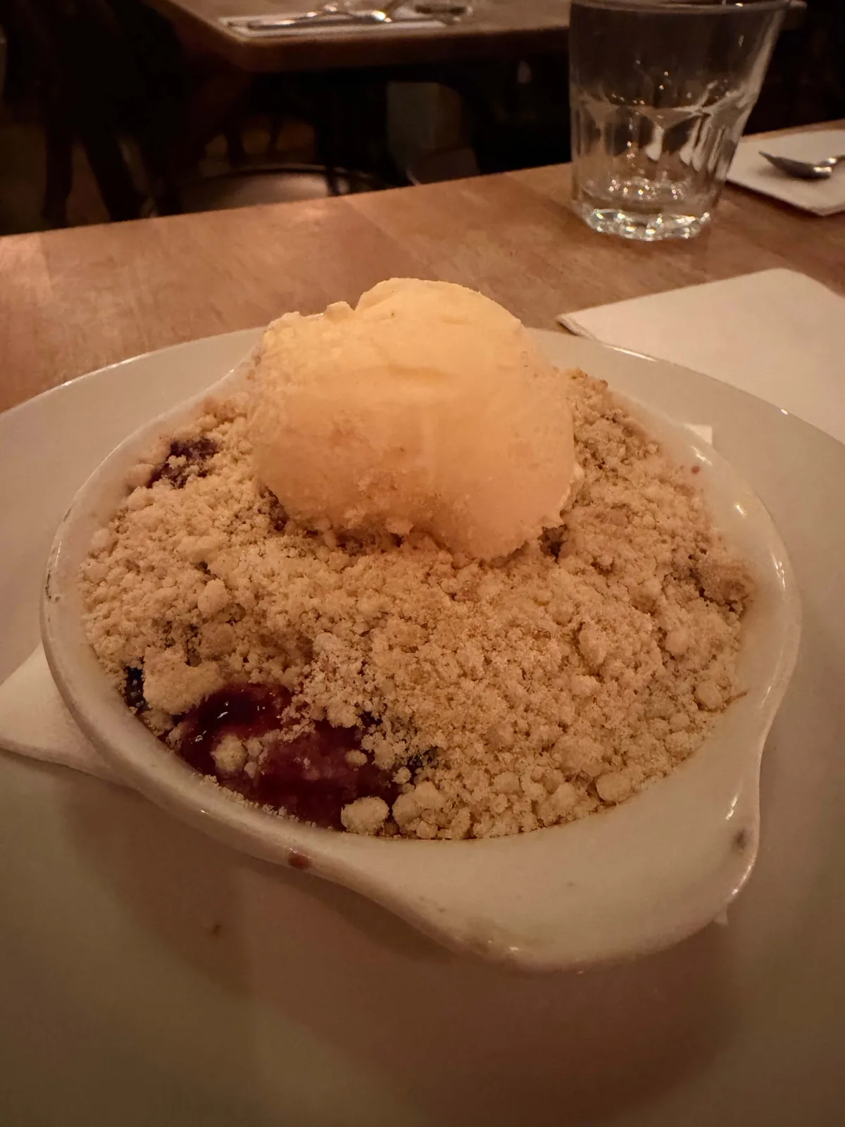 Fruit crumble with vanilla ice cream at Prix Fixe Brasserie Soho, golden on top with a deep red jammy layer underneath