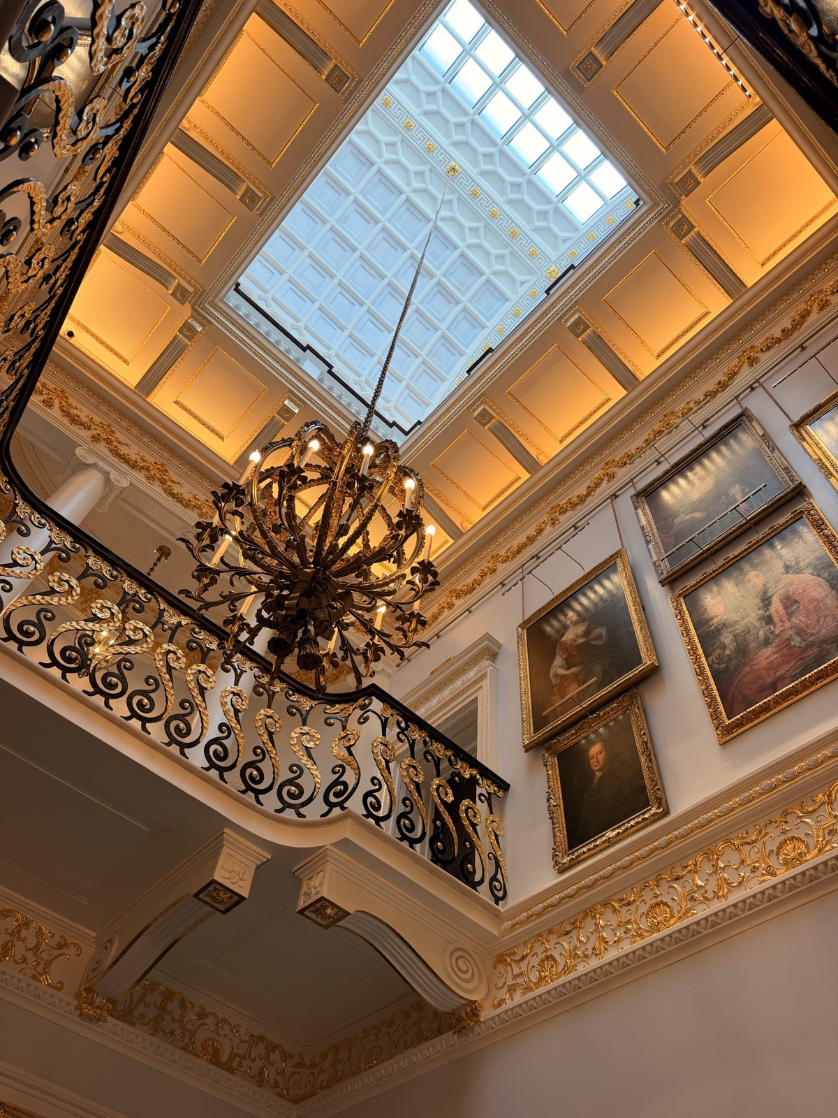 A chandelier hanging beneath the glazed skylight above the staircase at The Ritz London