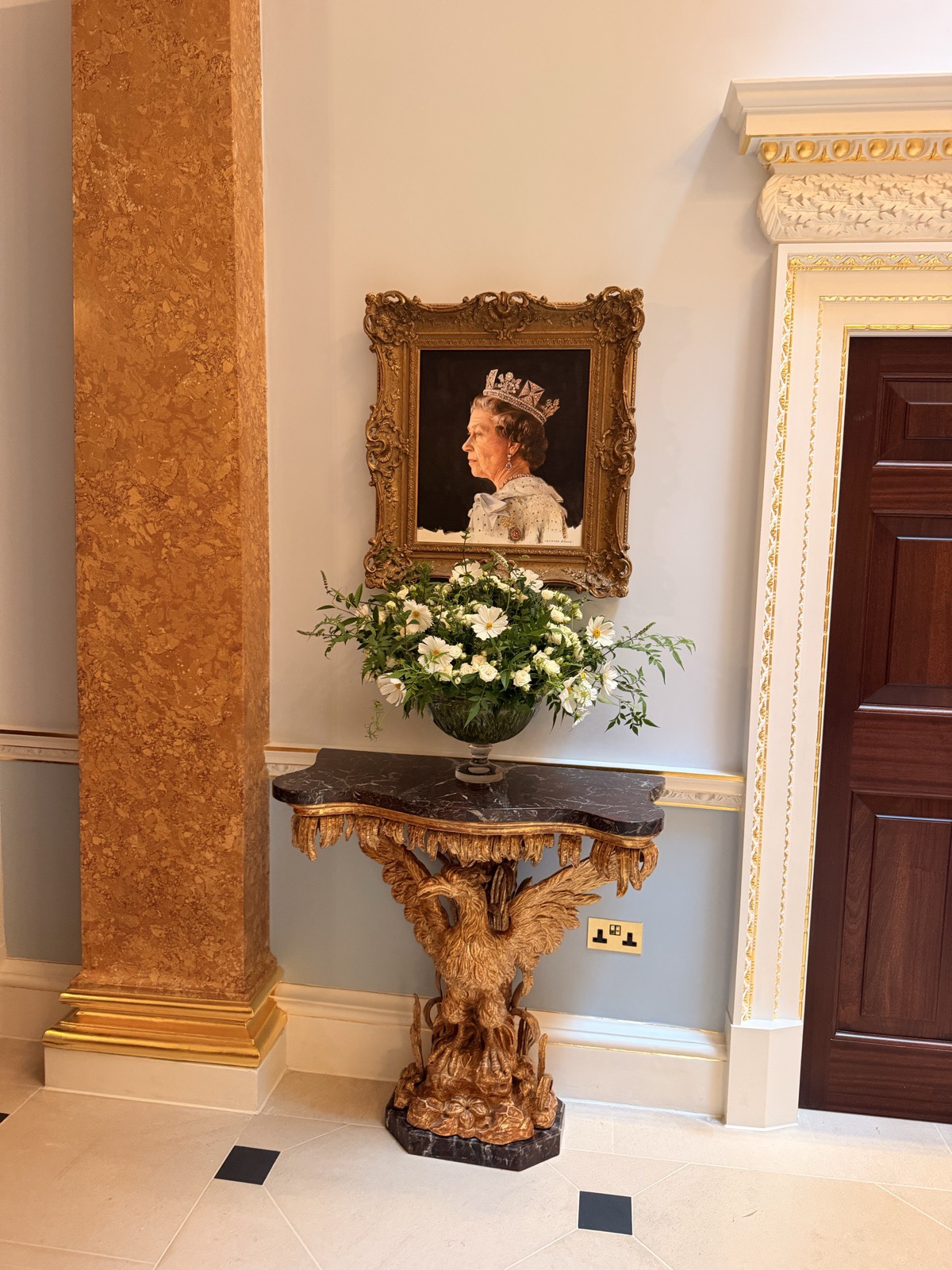 A portrait and fresh flowers on a console in the completely transformed entrance at The Ritz London