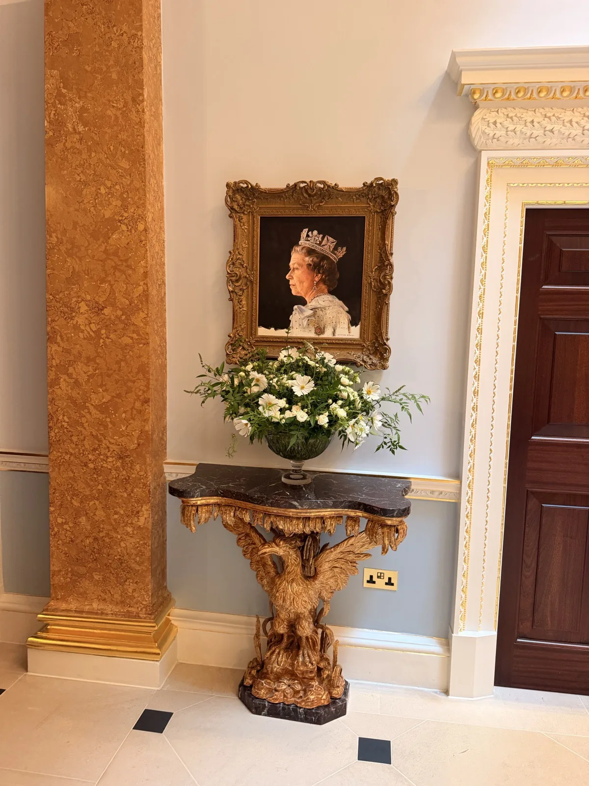 A portrait and fresh flowers on a console in the completely transformed entrance at The Ritz London