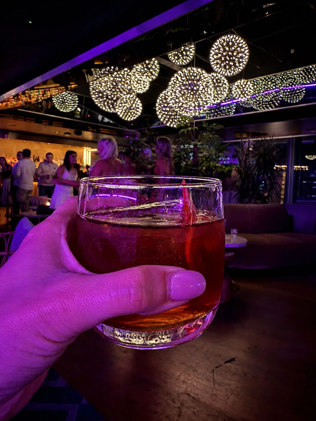 A cocktail held up under the lights at 12th Knot, the rooftop bar on the 12th floor of Sea Containers London