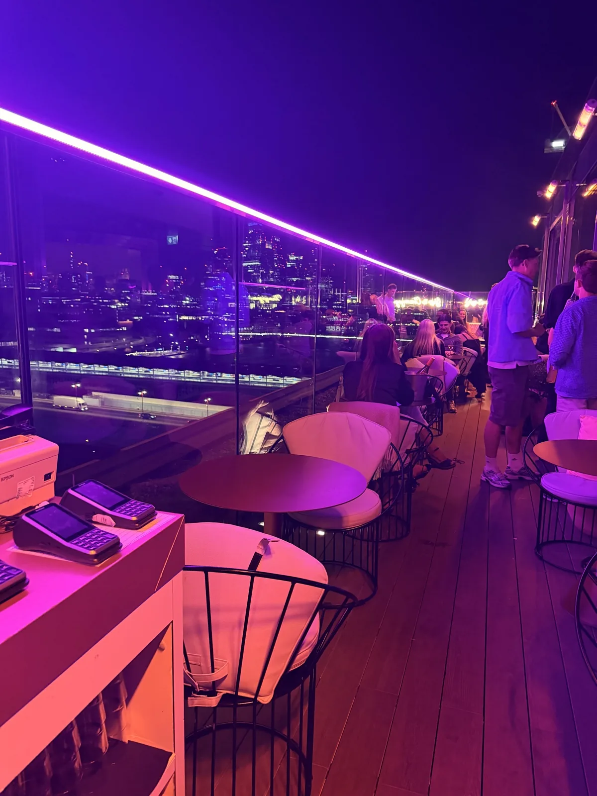 The City of London skyline at night from the 12th Knot rooftop bar at Sea Containers London, the terrace lit with violet neon