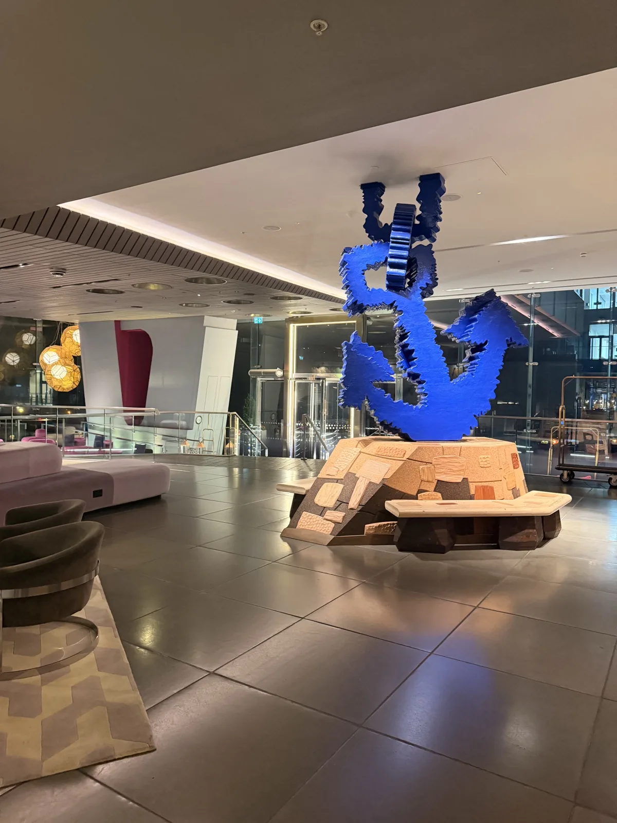 The enormous electric blue anchor sculpture in the Sea Containers London lobby, on a base of layered cork and timber blocks with Tom Dixon pendant lights above
