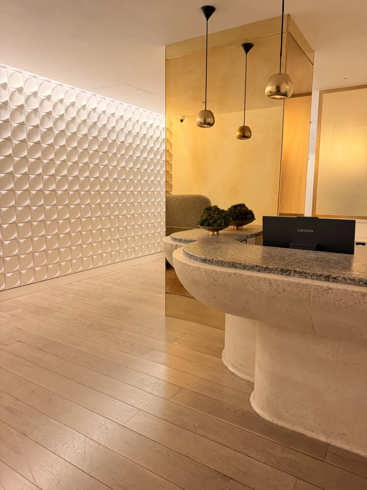 The entrance to agua spa at Sea Containers London, a carved stone desk against a quilted wall under brass pendants