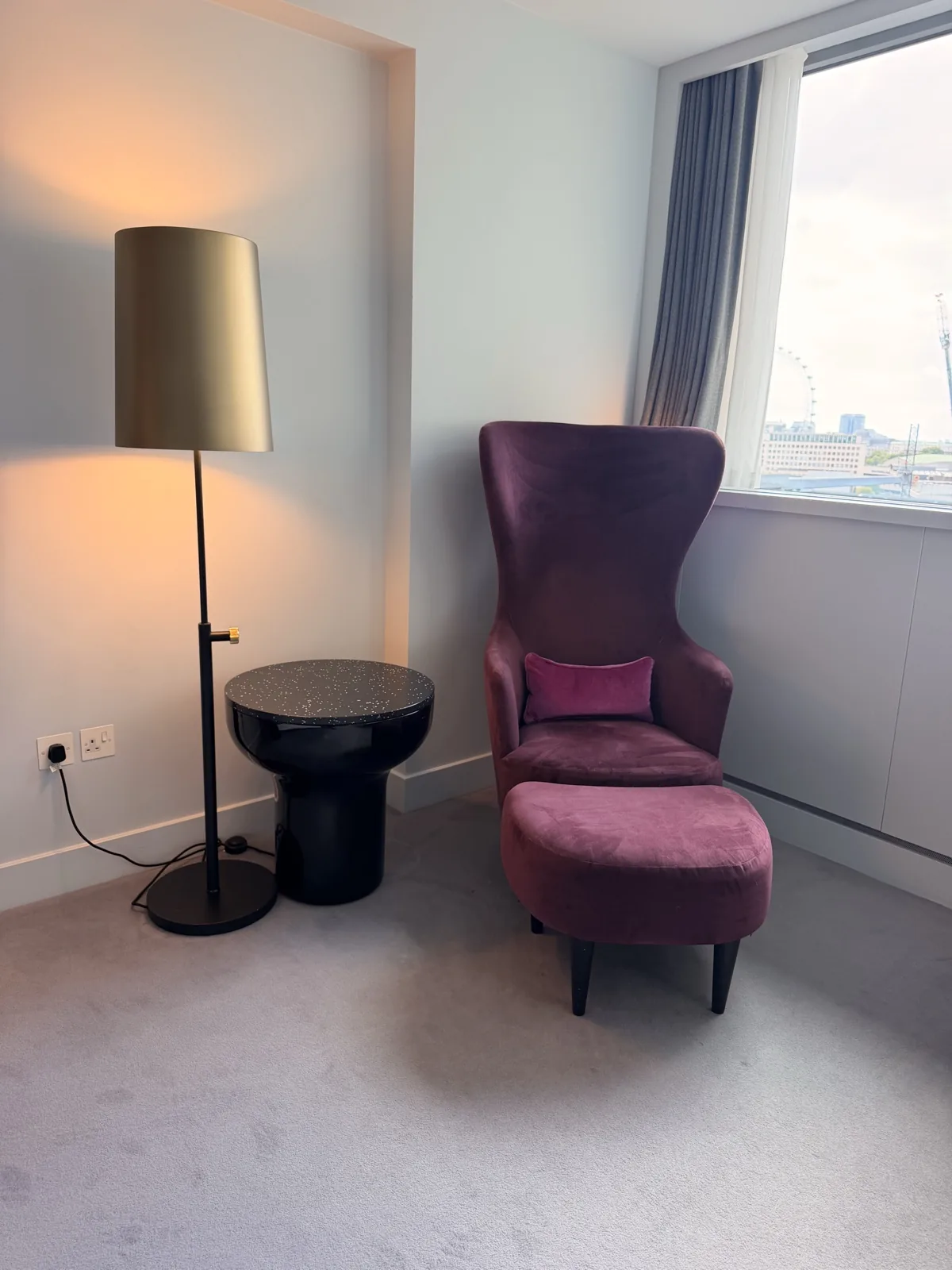 The single burgundy armchair, small side table and floor lamp that furnish one end of the room at Sea Containers London