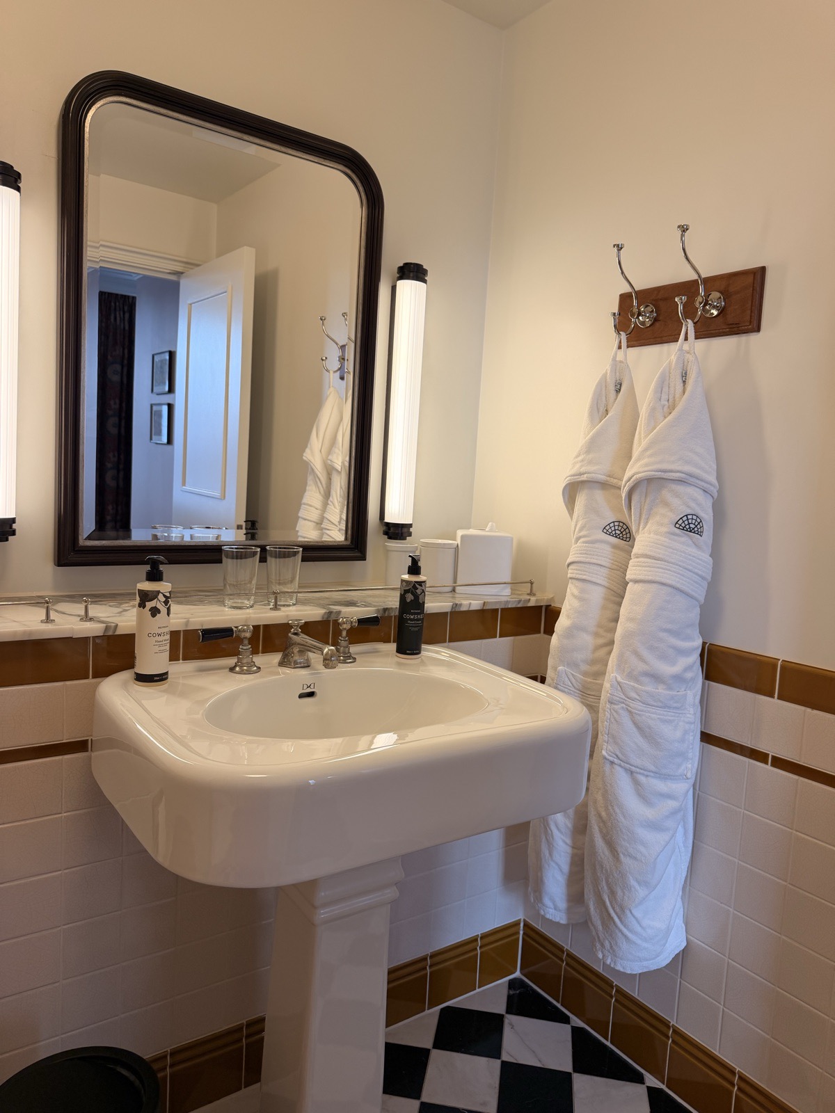 Cowshed toiletries and two folded robes in the marble bathroom at The Ned